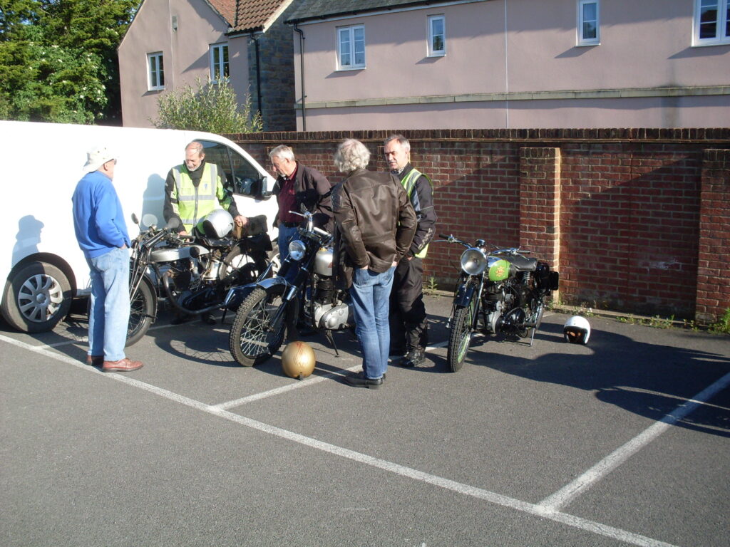 Five riders gathered around a vintage Norton