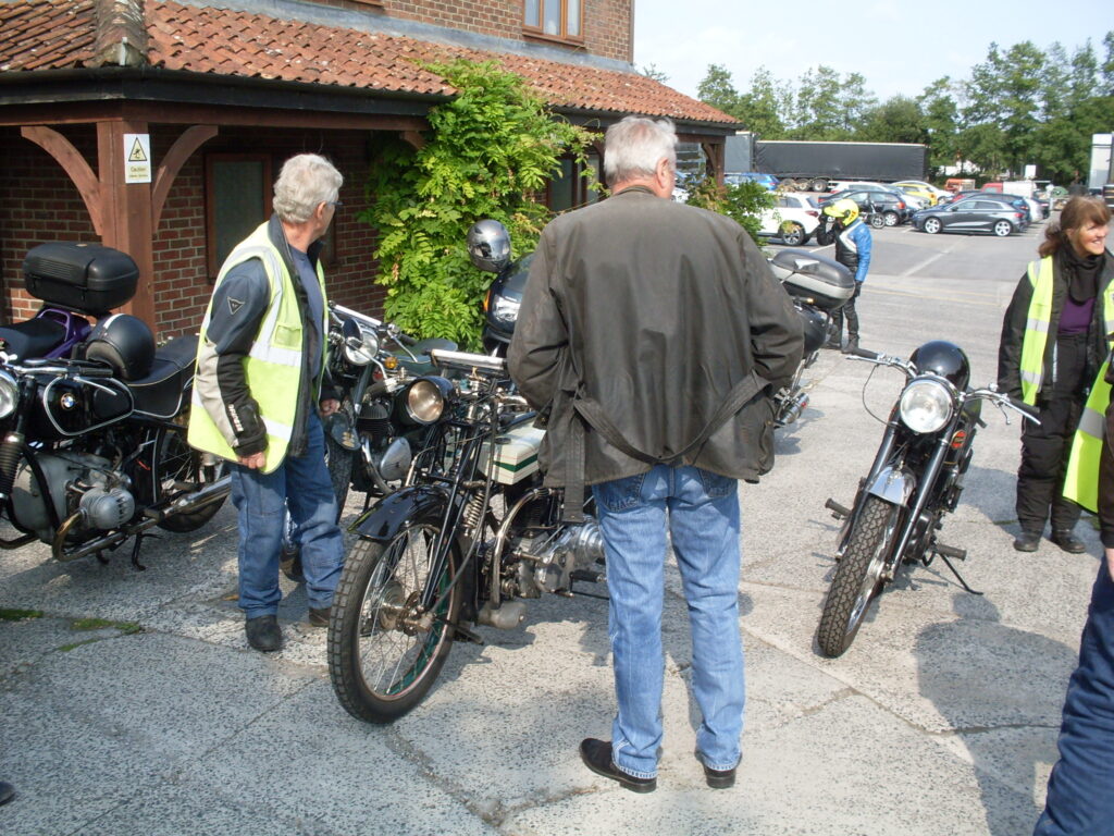 A vintage motorcyle between two people clearly looking somewhere else!