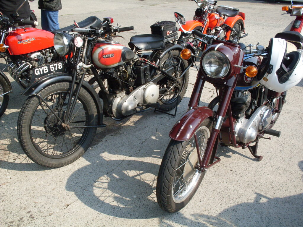 Five parked motorcycles (three in front. two behind). Two are almost all red, two have red tanks and the fifth (just in view behind) is red and white.