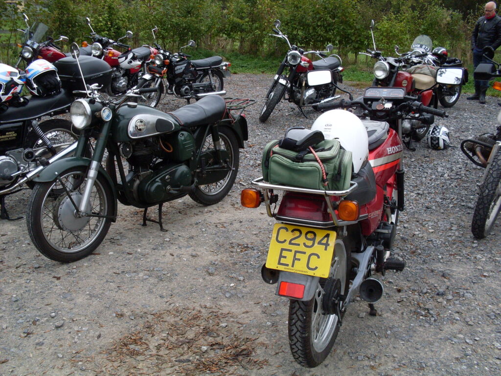 A dark green Norton in the middle of a group of motorcycles from the  1970s and 1980s 