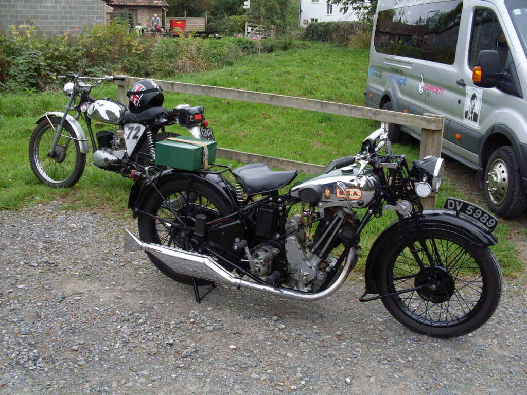 The off-road specification BSA Bantam  parked next to the pre-war BSA  with hand-change and a sloping engine. 
